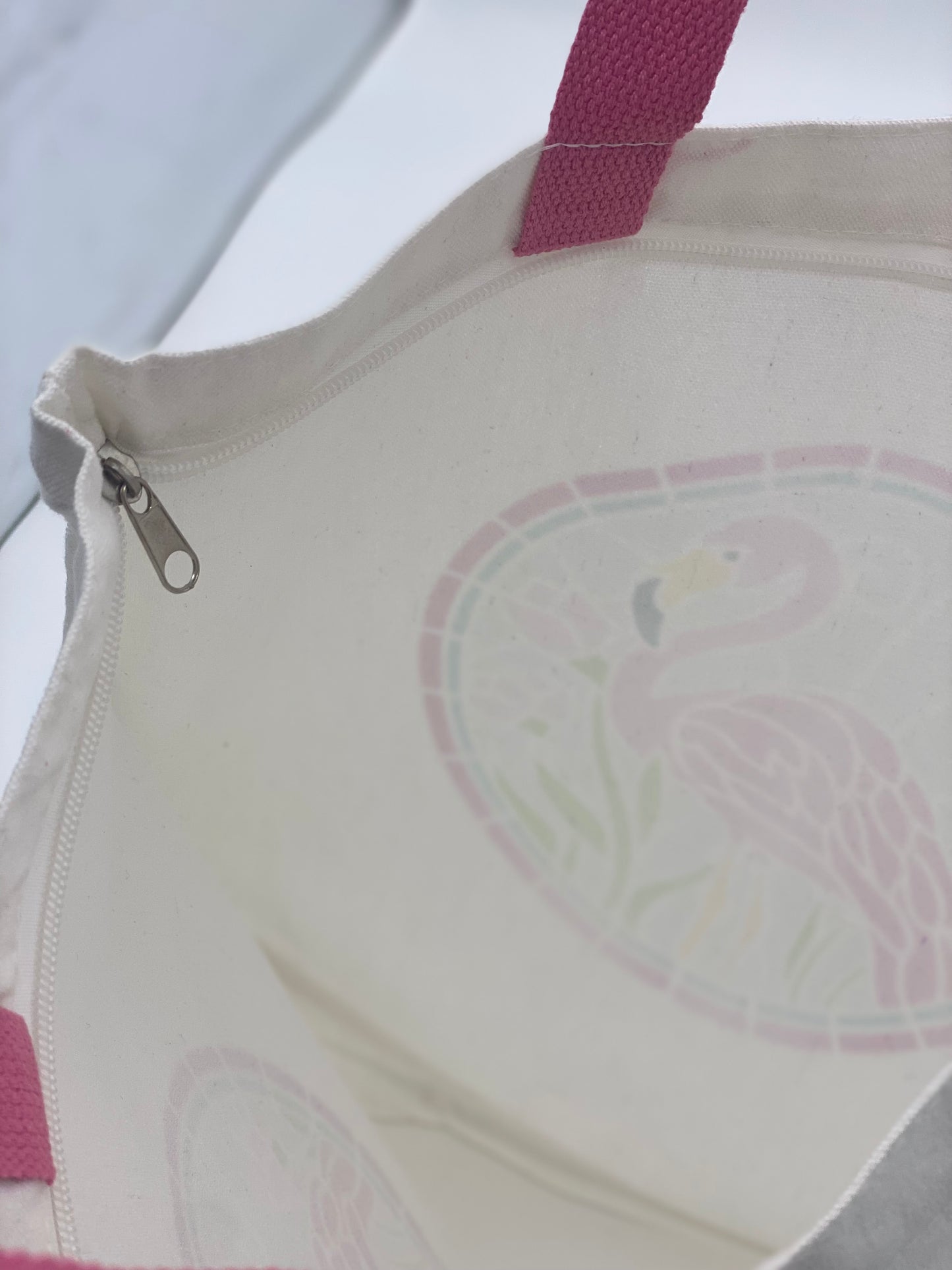 Close-up of inside white canvas bag with flamingo design featuring pink handles.