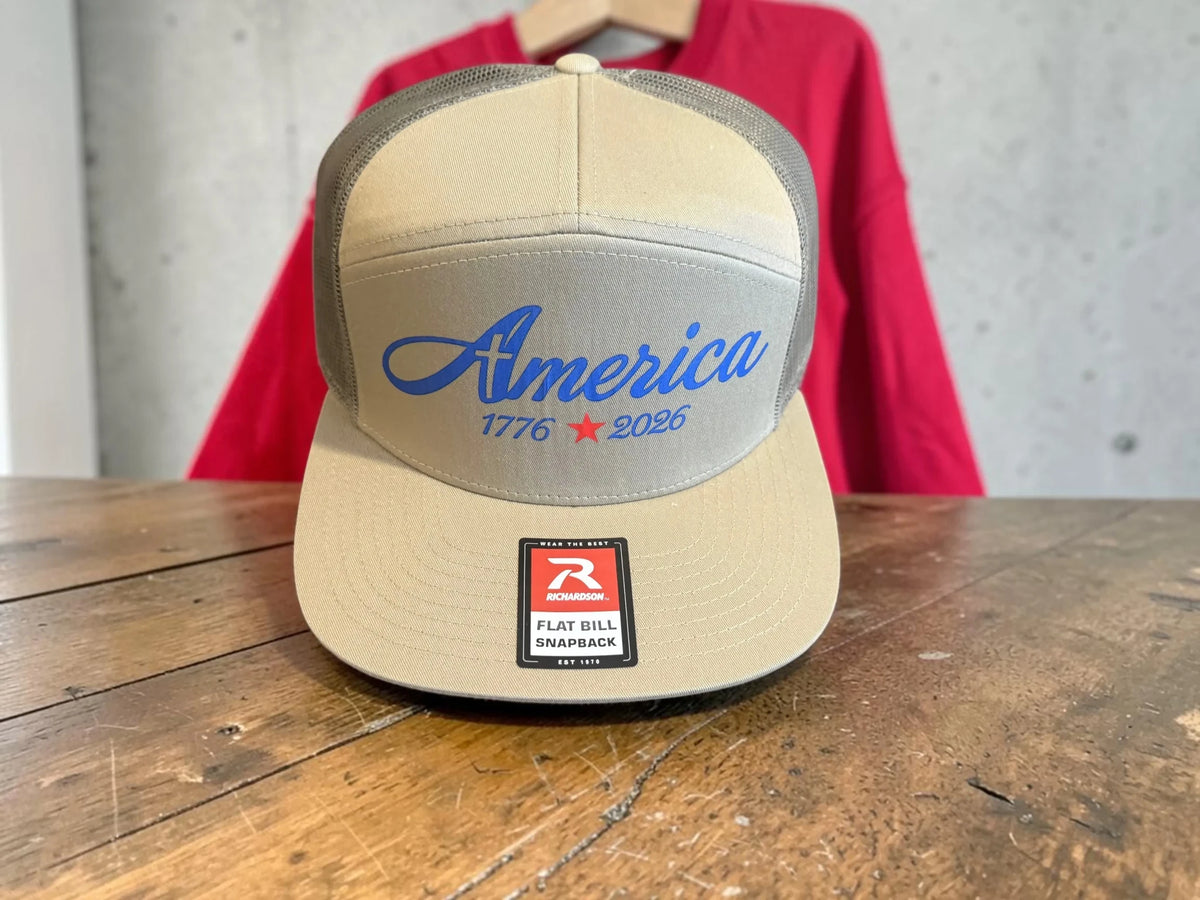 Seaside Custom Apparel & Gifts tan and grey Richardson flat bill snapback hat with America 1776-2026 blue embroidery