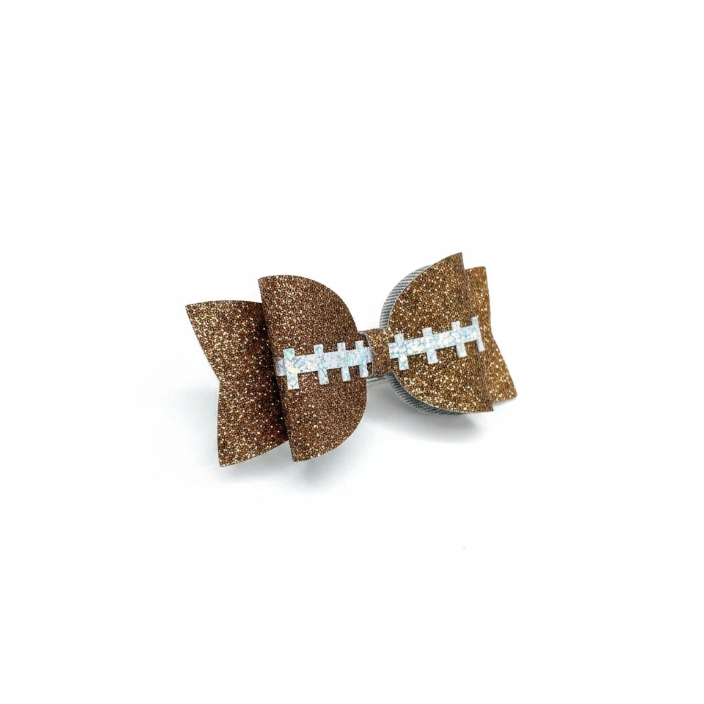 Seaside Custom Apparel & Gifts brown glitter football hair bow with white stitching detail on an alligator clip