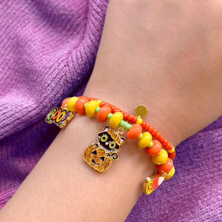 Seaside Custom Apparel & Gifts Halloween beaded bracelet with pumpkin, cat, and candy corn charms on a child's wrist.