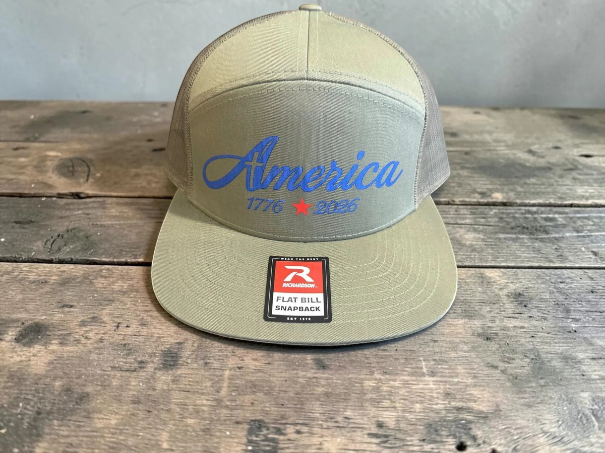 Seaside Custom Apparel & Gifts olive green Richardson trucker hat with blue America 1776-2026 graphic and flat bill