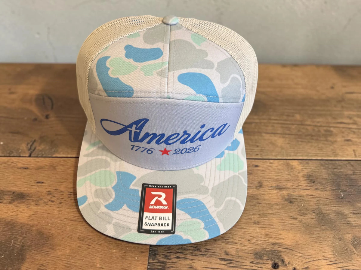 Seaside Custom Apparel & Gifts patriotic snapback hat with blue camo print, America graphic, and white mesh back.