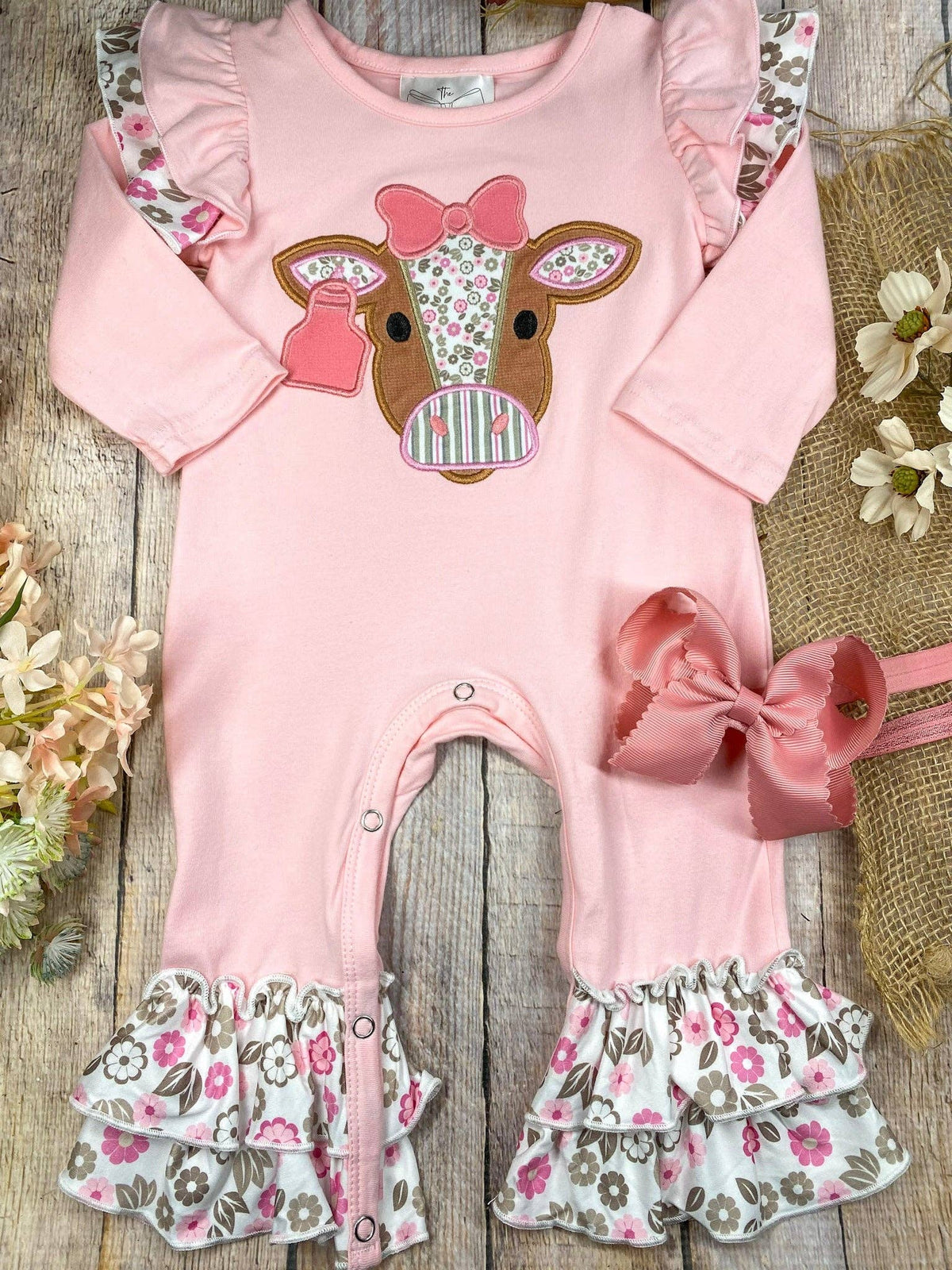 Seaside Custom Apparel & Gifts pink infant romper with floral cow applique, flutter shoulders, and ruffle leg trim.
