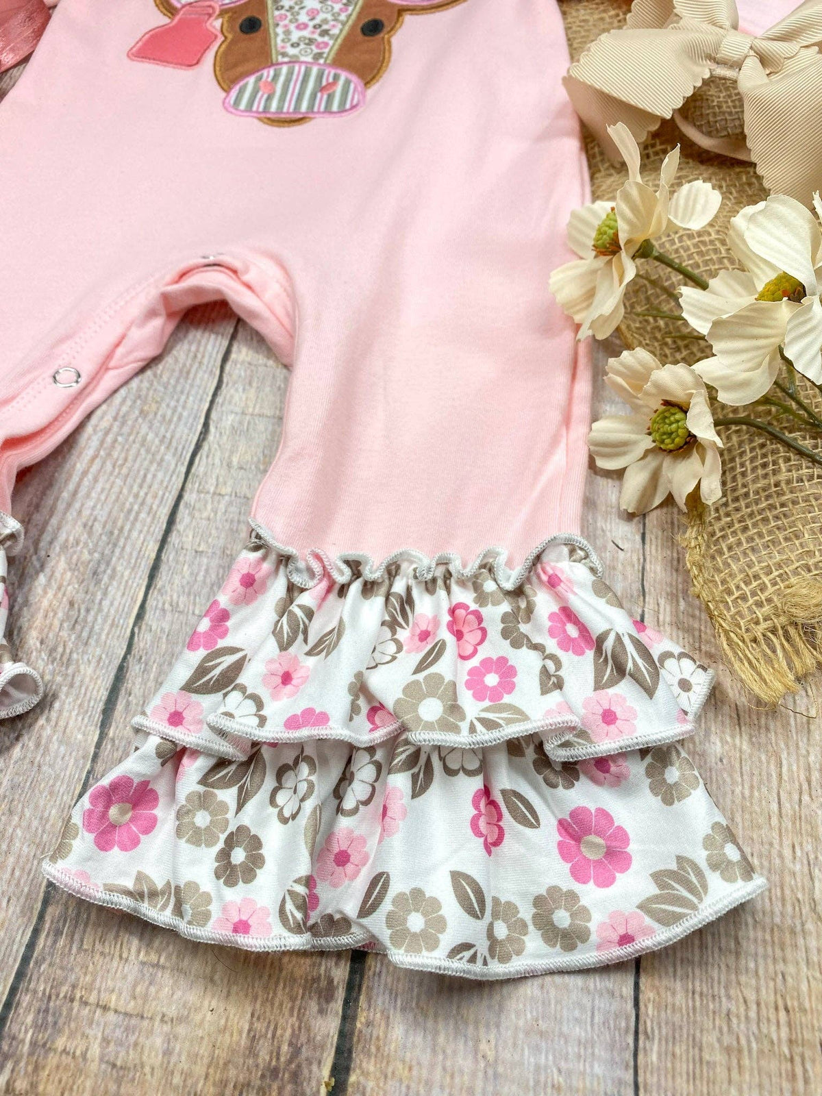 Seaside Custom Apparel & Gifts pink infant romper featuring floral ruffle leg trim and a cute cow applique design.