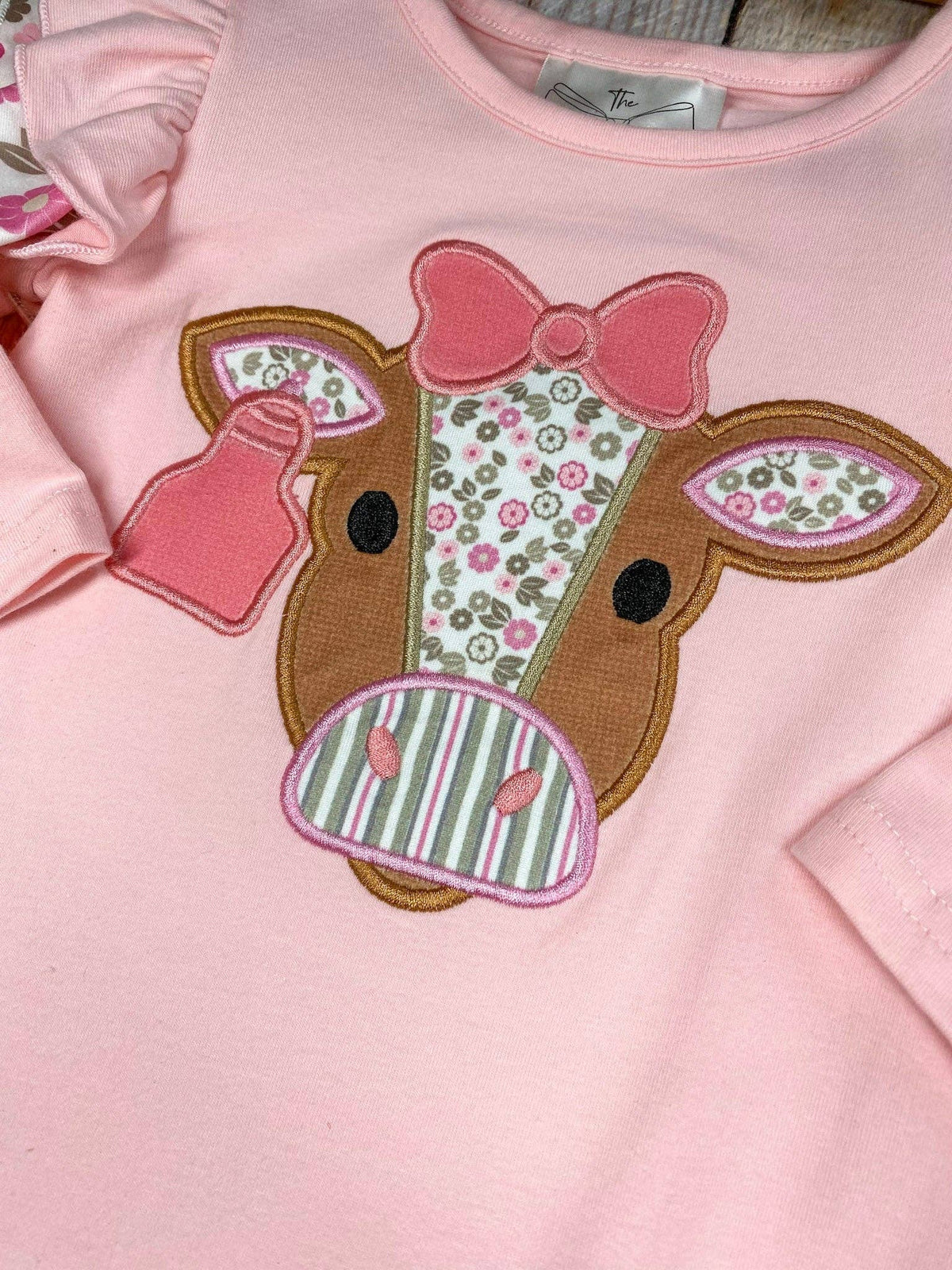 Seaside Custom Apparel & Gifts pink infant romper with floral cow applique, flutter shoulders, and bow detail