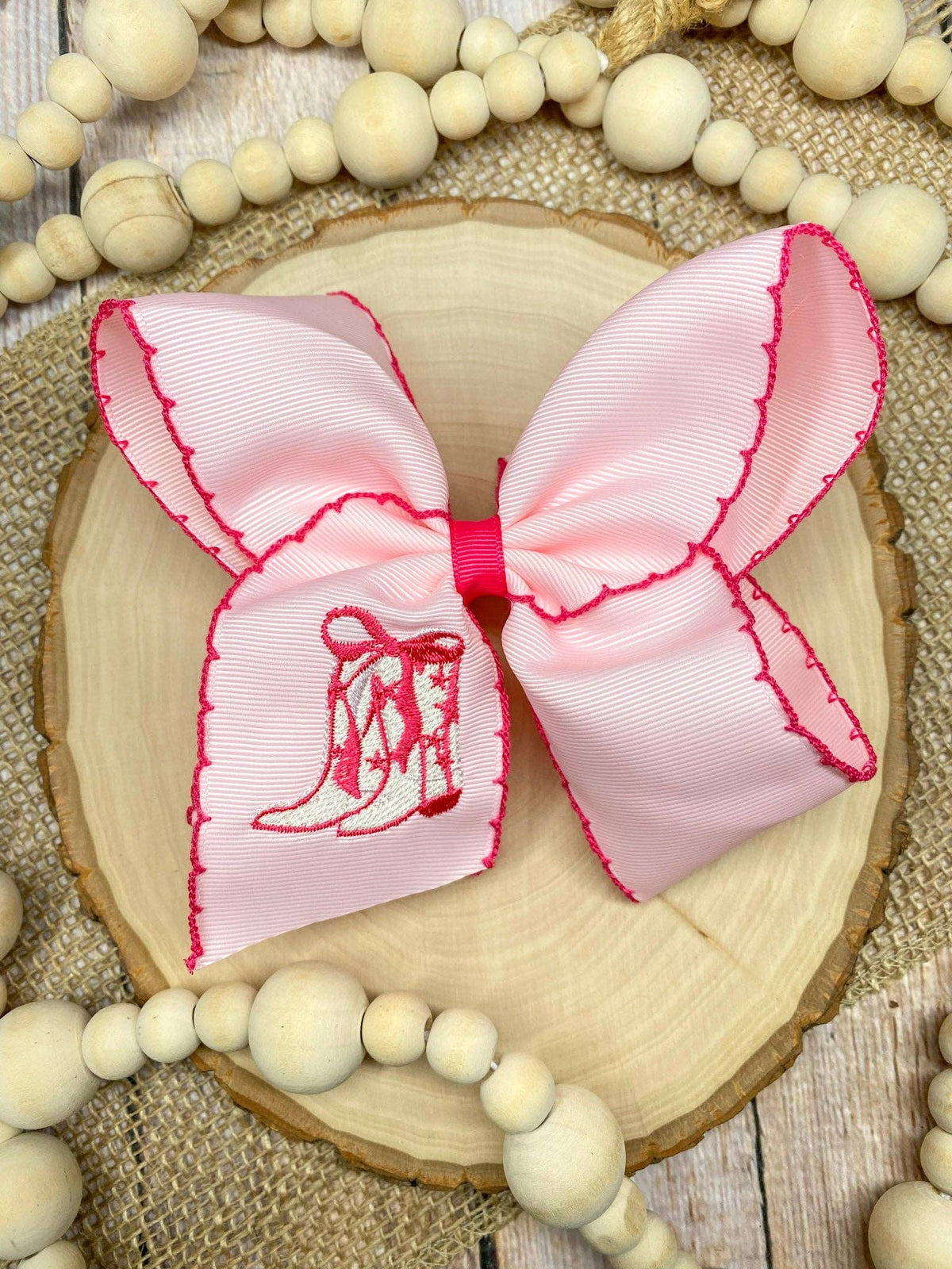 Seaside Custom Apparel & Gifts pink grosgrain hair bow with western boot embroidery and dark pink moonstitch trim.