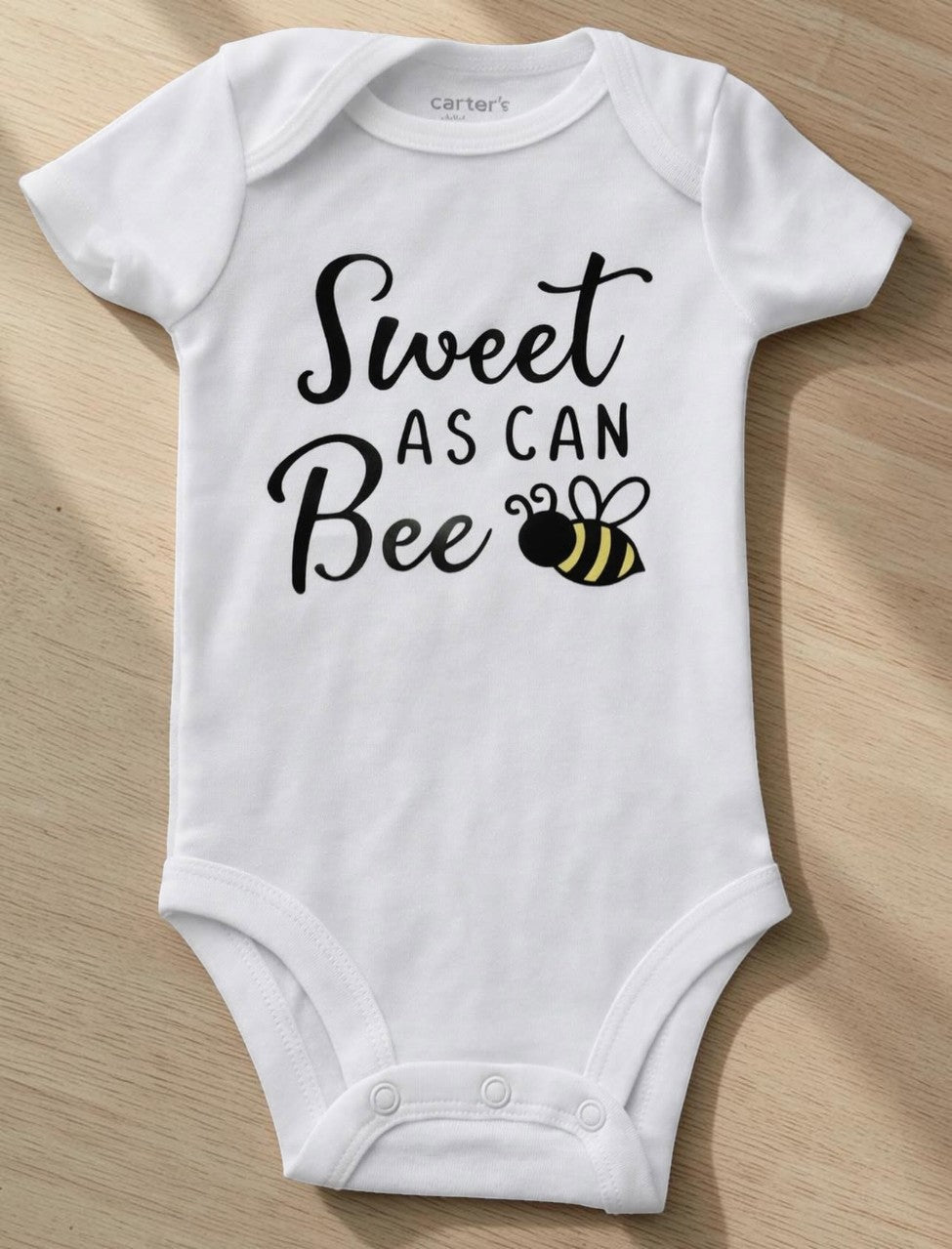 Seaside Custom Apparel & Gifts white cotton baby onesie with Sweet as can BEE graphic print and snap closures.