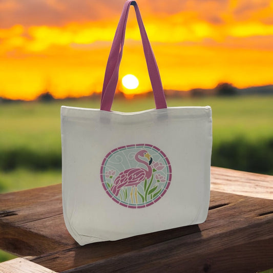 Tote bag with flamingo design on a wooden surface with a sunset background