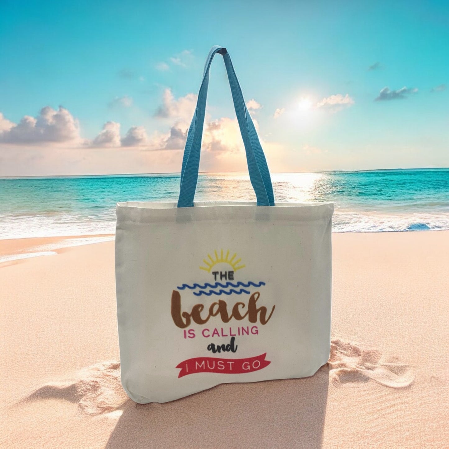 Tote bag with 'The beach is calling and I must go' text on a sandy beach with ocean view