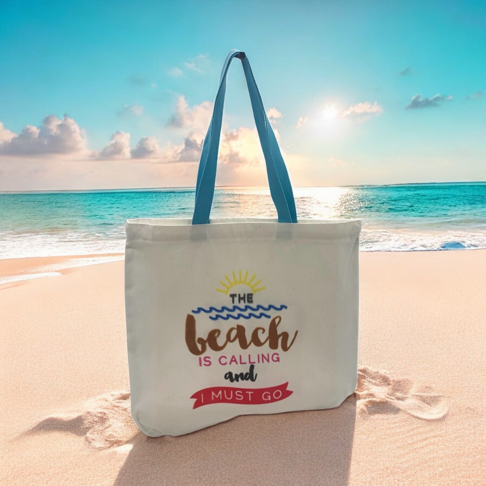 Tote bag with 'The beach is calling and I must go' text on a sandy beach with ocean view