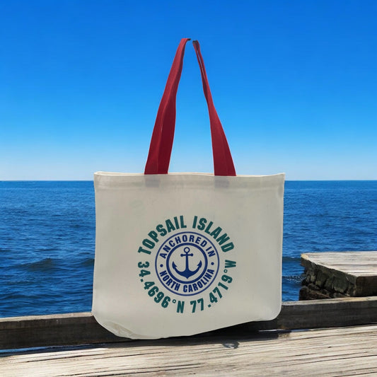 Tote bag with 'TopSail Island' cordinates design on a wooden dock with ocean view